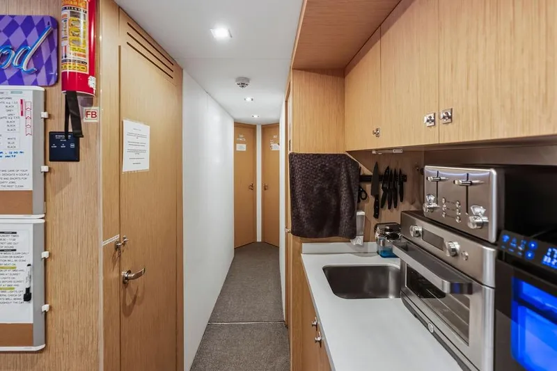 Slide: The Image of Compact yacht kitchen with modern appliances, wooden cabinets, and hallway view. Custom Line 120, 2018. - 120