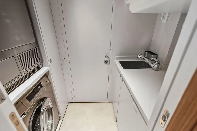 Slide: The Image of Compact laundry room with washer, dryer, and sink in a 2018 Custom Line 120 yacht. - 121