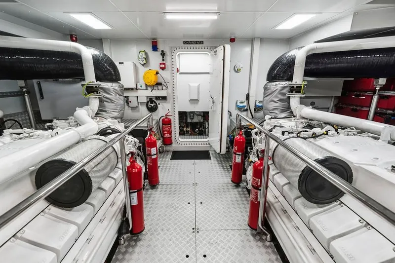 Slide: The Image of Engine room of a 2018 Custom Line 120 yacht, featuring dual engines and safety equipment. - 129