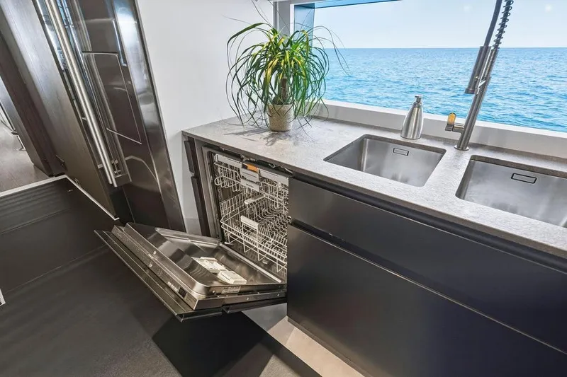 Slide: The Image of Modern yacht kitchen with open dishwasher, dual sinks, ocean view, and potted plant. Custom Line 120, 2018. - 66
