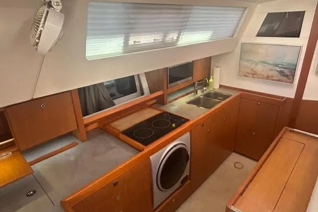 Slide: The Image of Interior of 2013 Beneteau Sense 46 yacht kitchen with wood cabinetry and modern appliances. - 47