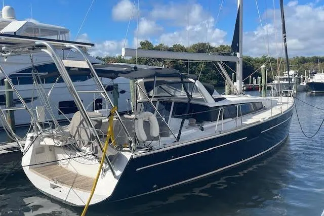 Slide: The Image of 2013 Beneteau Sense 46 sailboat docked in a marina under a clear blue sky. - 78