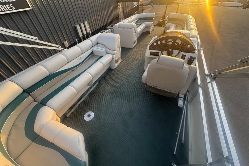 Slide: The Image of 2002 Bennington 2550RL pontoon boat interior with plush seating and steering console at sunset. - 13