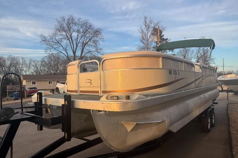 Slide: The Image of 2002 Bennington 2550RL pontoon boat on trailer, parked outdoors under a clear sky. - 2