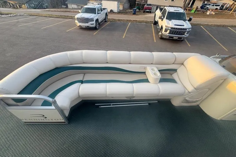 Slide: The Image of 2002 Bennington 2550RL boat with white and teal seating in a parking lot. - 6