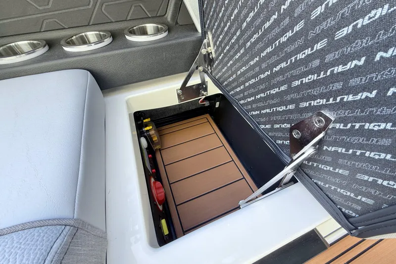 Slide: The Image of 2026 Nautique Super Air Nautique GS22 storage compartment with cushioned seating and cup holders. - 19