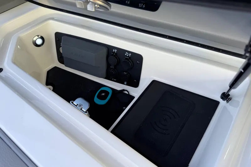 Slide: The Image of 2026 Nautique Super Air Nautique GS22 storage compartment with charging pad and controls. - 22