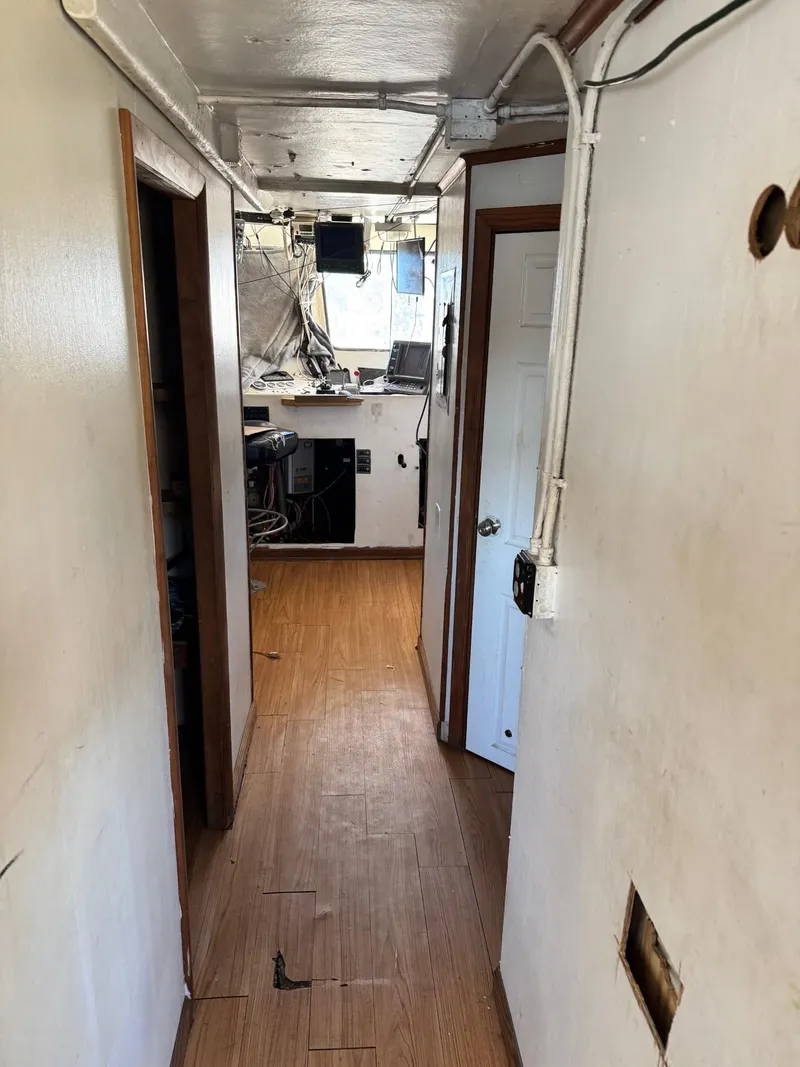 Slide: The Image of Narrow hallway inside 1971 Butterfish Fishing Trawler, featuring wooden flooring and visible wiring. - 14