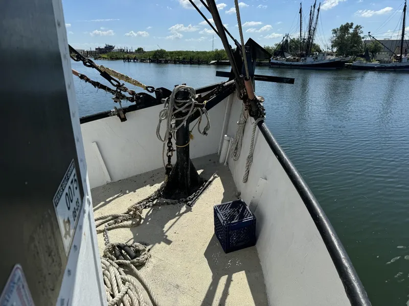Slide: The Image of 1972 commercial shrimp freezer trawler deck with ropes and crate, docked by calm waters. - 1