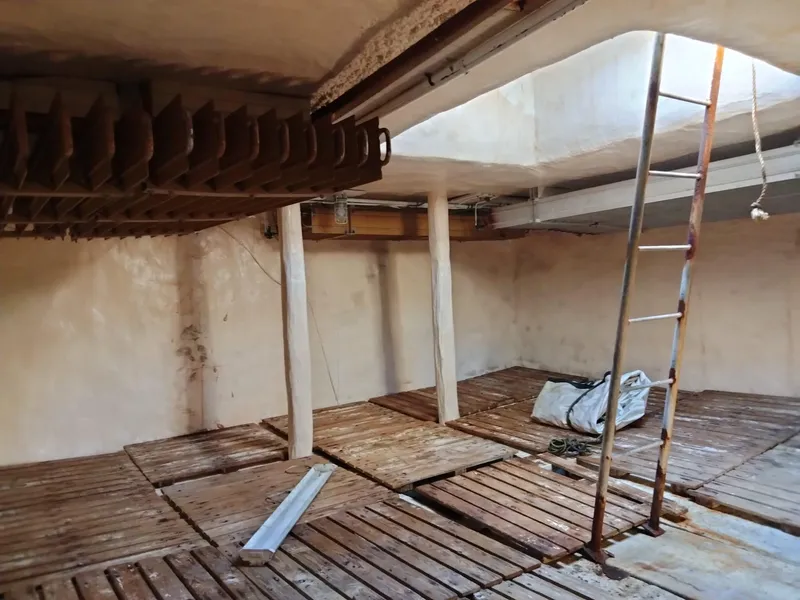 Slide: The Image of Interior of a 1972 commercial shrimp freezer trawler with wooden flooring and ladder. - 15