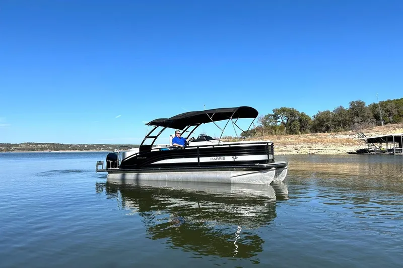 Slide: The Image of 2020 Harris FloteBote Solstice 230 pontoon boat on a calm lake under clear blue skies. - 13
