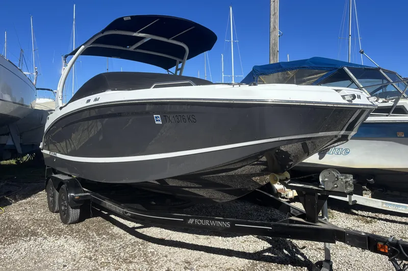 Slide: The Image of 2023 Four Winns HD3 boat on trailer, parked in marina under clear blue sky. - 1