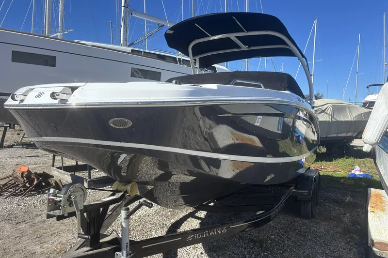 Slide: The Image of 2023 Four Winns HD3 boat on trailer, docked outdoors under clear blue sky. - 2