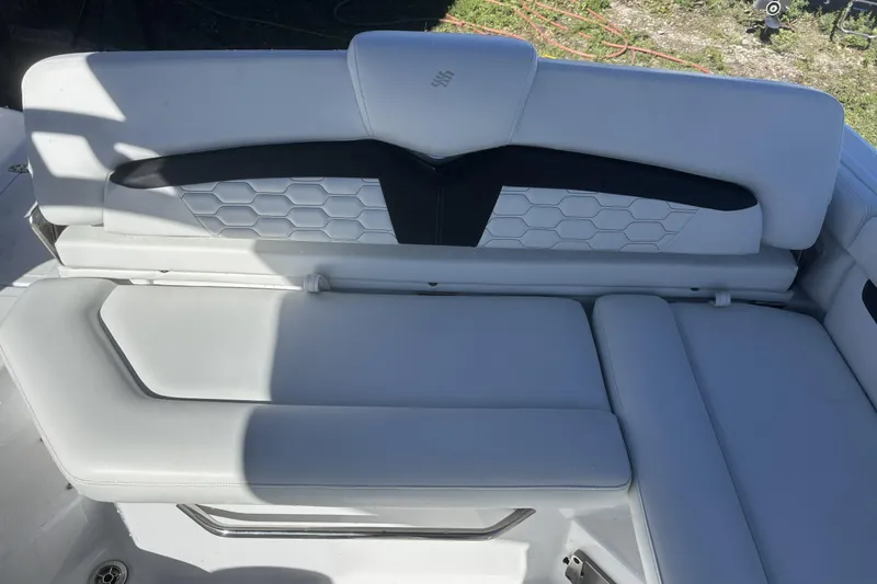 Slide: The Image of 2023 Four Winns HD3 boat interior with white cushioned seating and hexagonal pattern design. - 28
