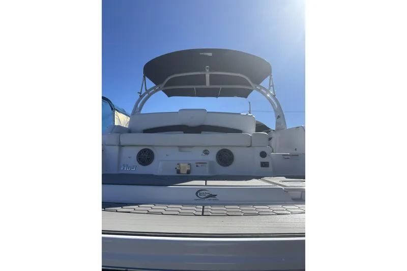 Slide: The Image of 2023 Four Winns HD3 boat rear view with seating and canopy under clear sky. - 4
