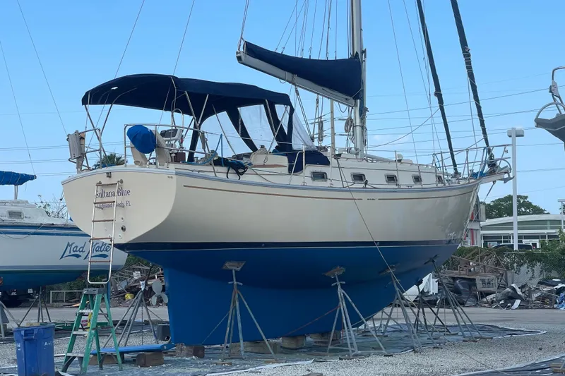 The Image of 1990 Island Packet 35 Cutter sailboat on dry dock, with blue hull and canopy. - 0