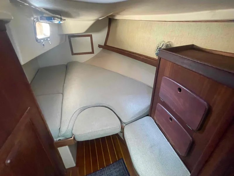 Slide: The Image of 1990 Island Packet 35 Cutter cabin interior with cushioned berth and wooden storage. - 13