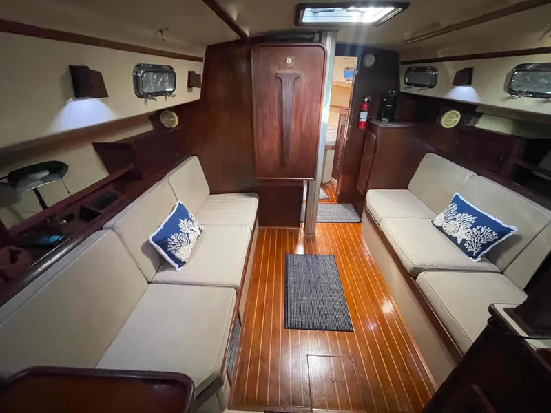 Slide: The Image of Interior of 1990 Island Packet 35 Cutter sailboat with cushioned seating and wooden cabinetry. - 22