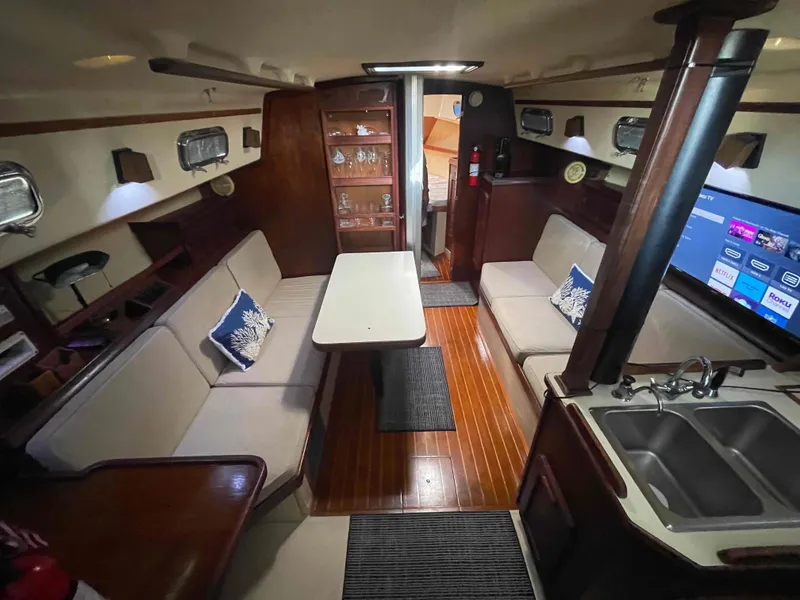 Slide: The Image of 1990 Island Packet 35 Cutter sailboat interior cabin with wooden finishes and a V-berth. - 23