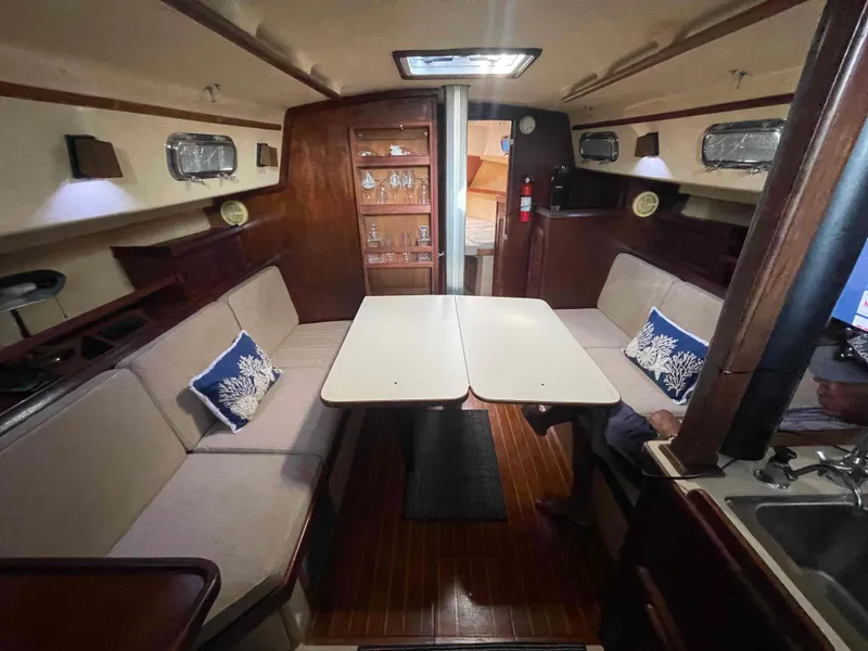 Slide: The Image of Interior of 1990 Island Packet 35 Cutter sailboat with wooden flooring and cushioned seating. - 25
