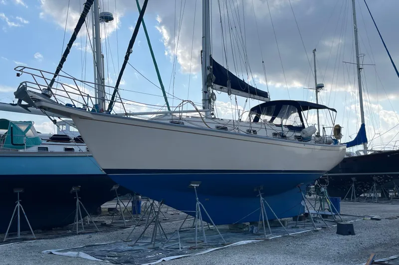 Slide: The Image of 1990 Island Packet 35 Cutter sailboat on stands, under a cloudy sky. - 3