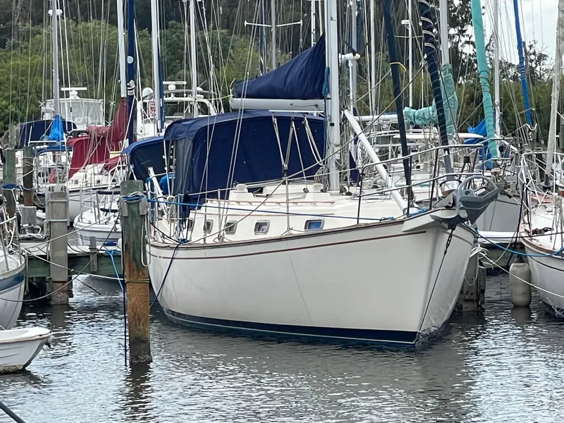 Slide: The Image of 1990 Island Packet 35 Cutter sailboat with blue canvas cover docked at marina. - 63