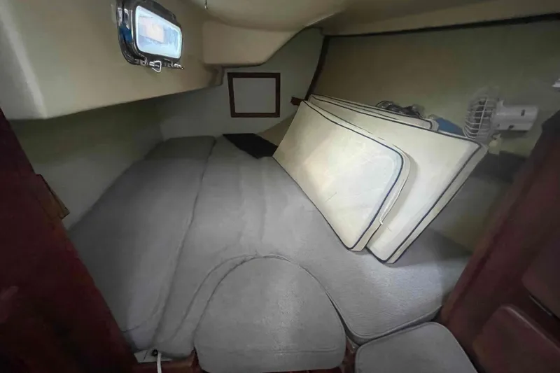 Slide: The Image of 1990 Island Packet 35 Cutter cabin interior with cushions and porthole. - 75