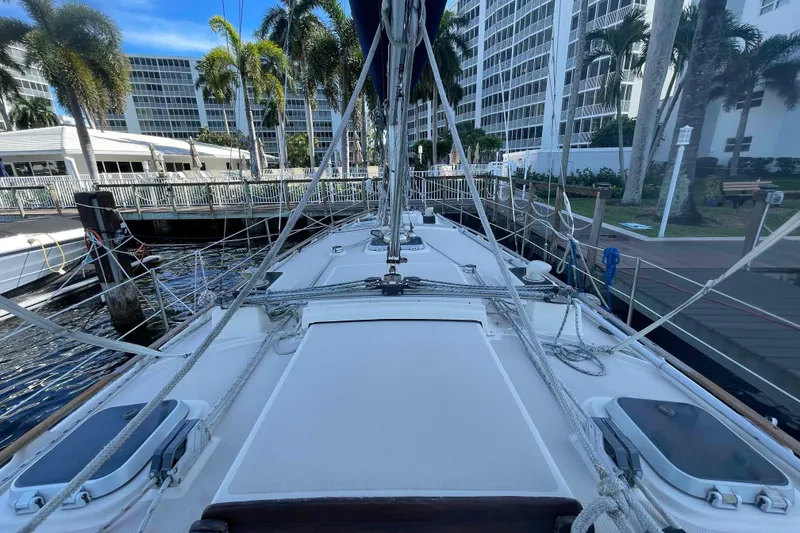 Slide: The Image of 1990 Island Packet 35 Cutter sailboat docked, surrounded by palm trees and buildings. - 79