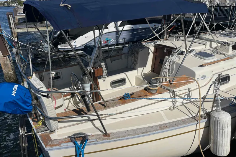Slide: The Image of 1990 Island Packet 35 Cutter sailboat docked, featuring a spacious cockpit and protective canopy. - 88