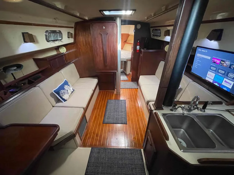 Slide: The Image of Interior of 1990 Island Packet 35 Cutter sailboat with wood finish and cozy seating. - 9