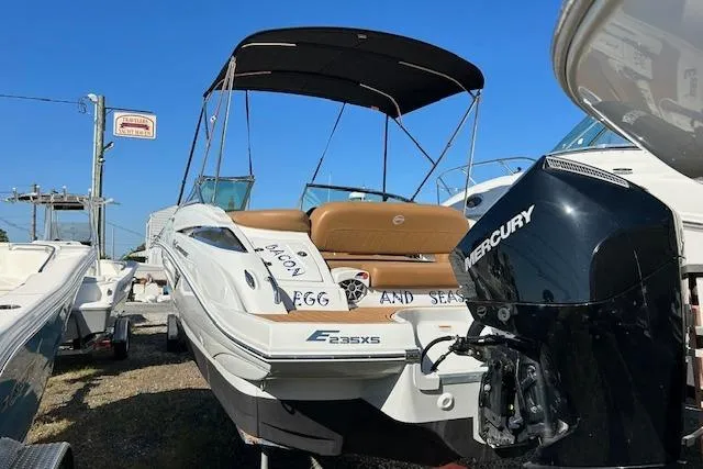 Slide: The Image of 2023 Crownline Eclipse E235 XS boat with Mercury engine, docked under a sunny sky. - 2