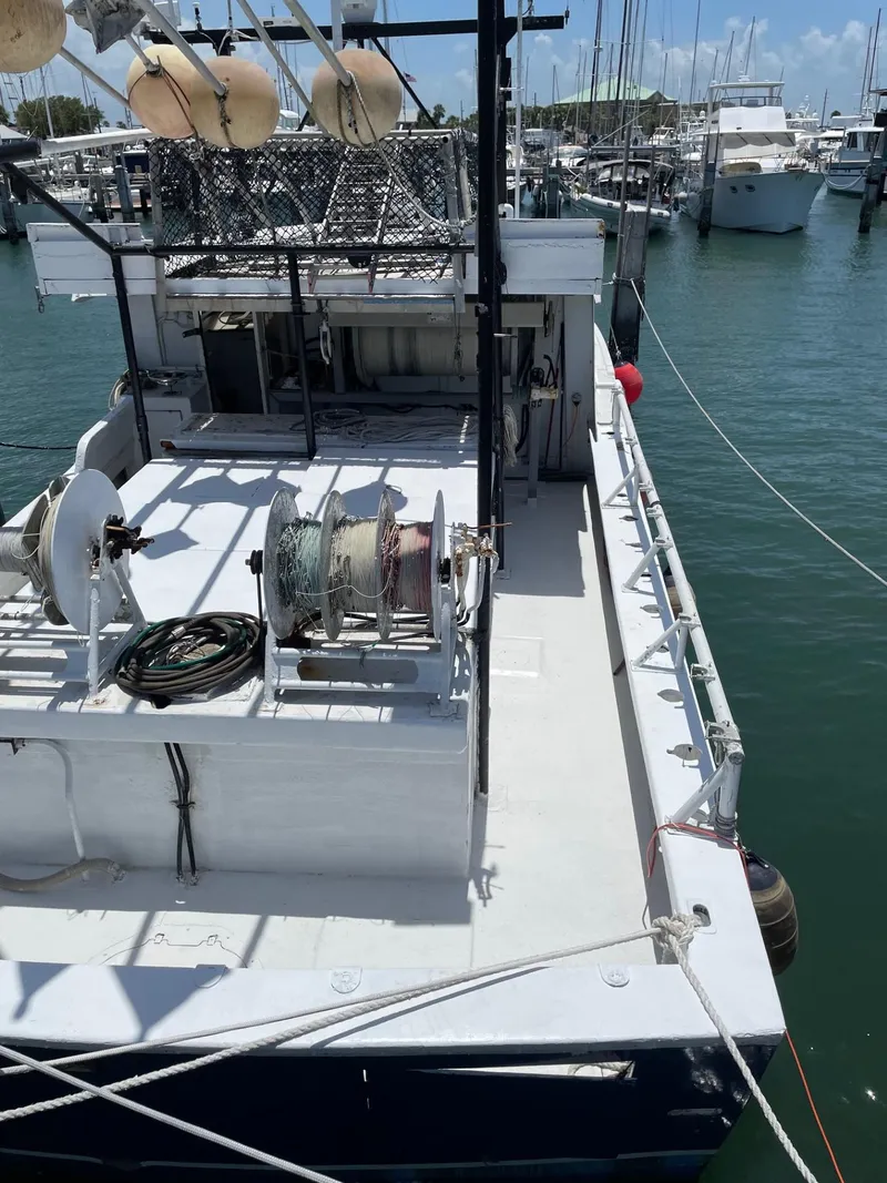 Slide: The Image of 1983 Commercial Hull #1 Key West boat docked at marina, featuring fishing equipment. - 19