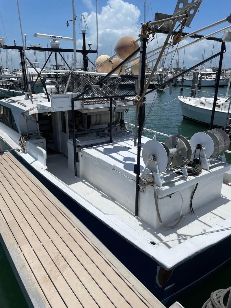 Slide: The Image of 1983 Commercial Hull #1 Key West boat docked at marina, clear sky, fishing equipment visible. - 20