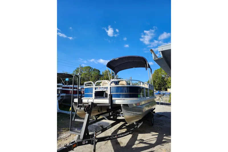 Slide: The Image of 2022 Sun Tracker Bass Buggy 16 XL Select pontoon boat on trailer under clear blue sky. - 3