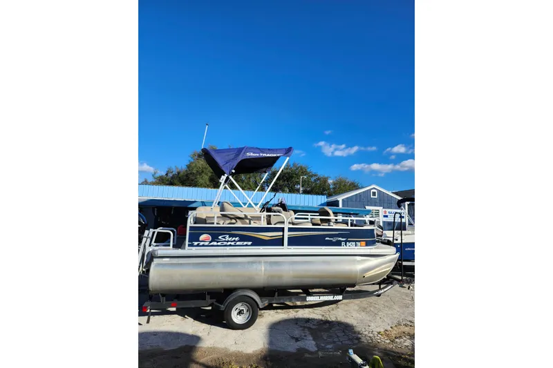 Slide: The Image of 2022 Sun Tracker Bass Buggy 16 XL Select pontoon boat on trailer under clear blue sky. - 6