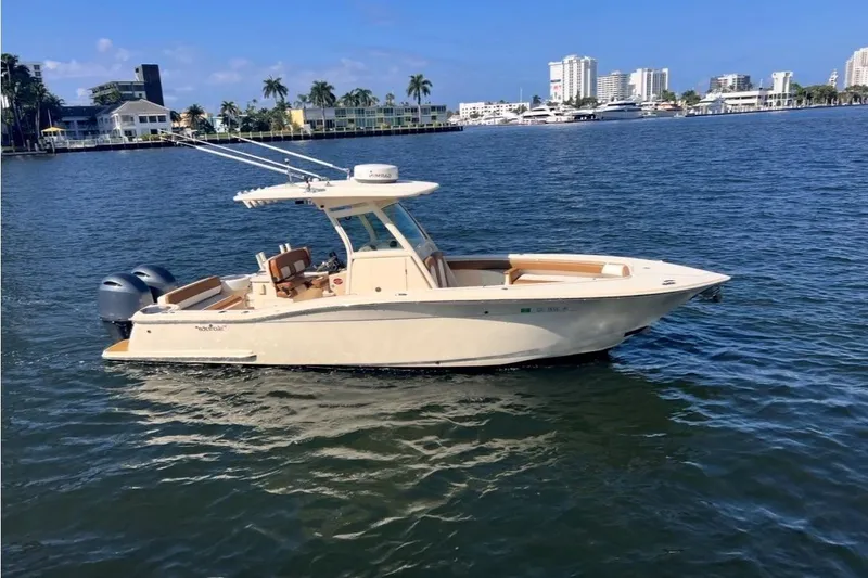 The Image of 2013 Scout 275 LXF boat on calm water with city skyline background. - 0
