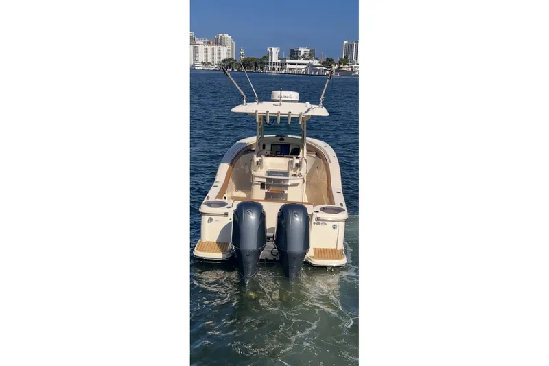 Slide: The Image of 2013 Scout 275 LXF boat with dual engines on water, city skyline in background. - 20