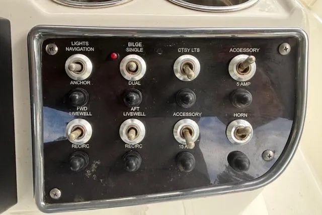 Slide: The Image of Control panel of 2021 NauticStar 211 Hybrid boat with various switches and indicators. - 13