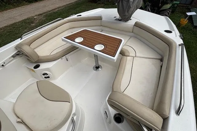 Slide: The Image of 2021 NauticStar 211 Hybrid boat interior with cushioned seating and a wooden table. - 6
