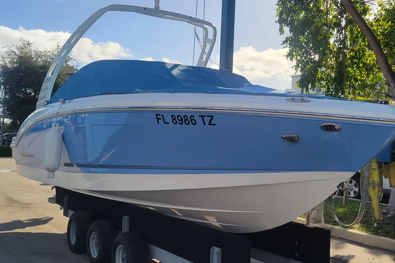 Slide: The Image of 2025 Chaparral 21 SSi OB boat on trailer, blue cover, sunny day. - 1