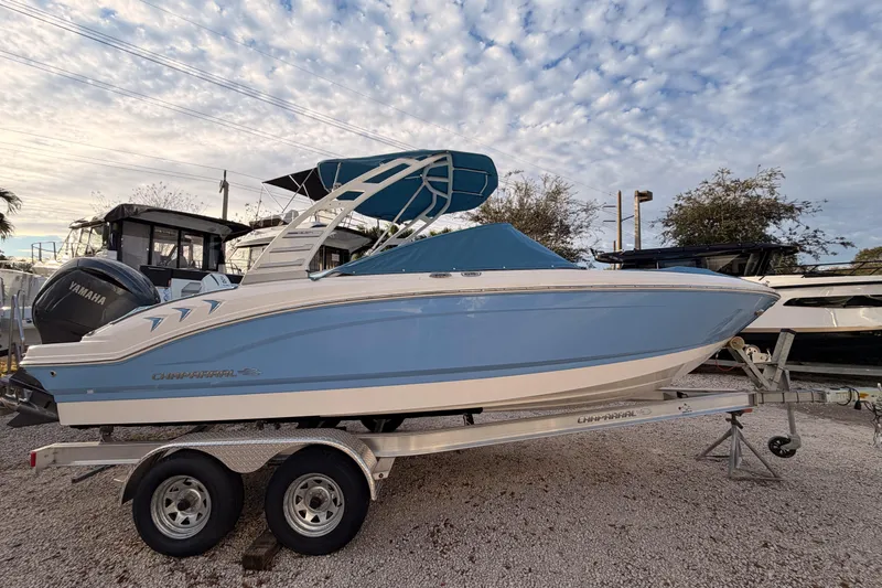 Slide: The Image of 2025 Chaparral 21 SSi OB boat on trailer, blue and white design, under cloudy sky. - 3