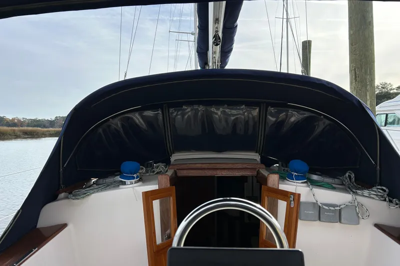 Slide: The Image of 1997 Island Packet 29 sailboat cockpit with blue canopy and open cabin doors. - 13