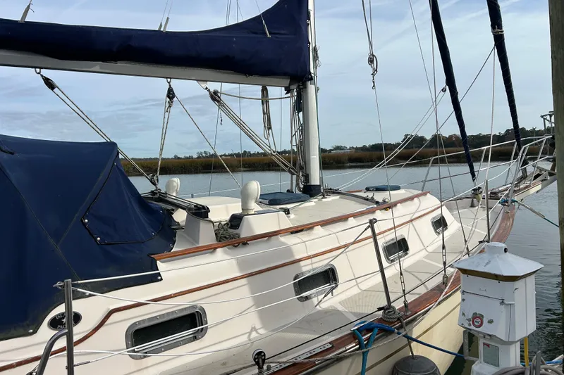 Slide: The Image of 1997 Island Packet 29 sailboat docked, featuring blue canvas covers and wooden trim. - 20