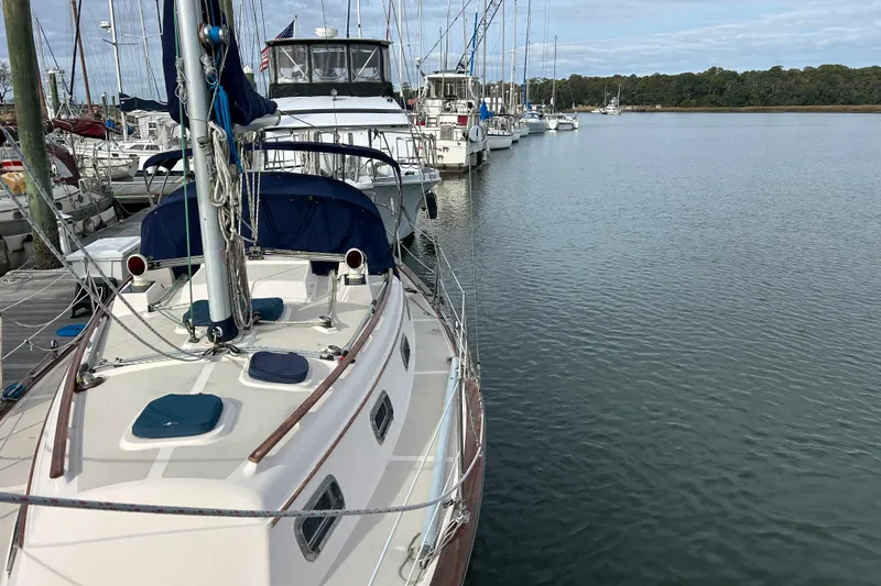 Slide: The Image of 1997 Island Packet 29 sailboat docked in a marina, surrounded by other boats. - 22