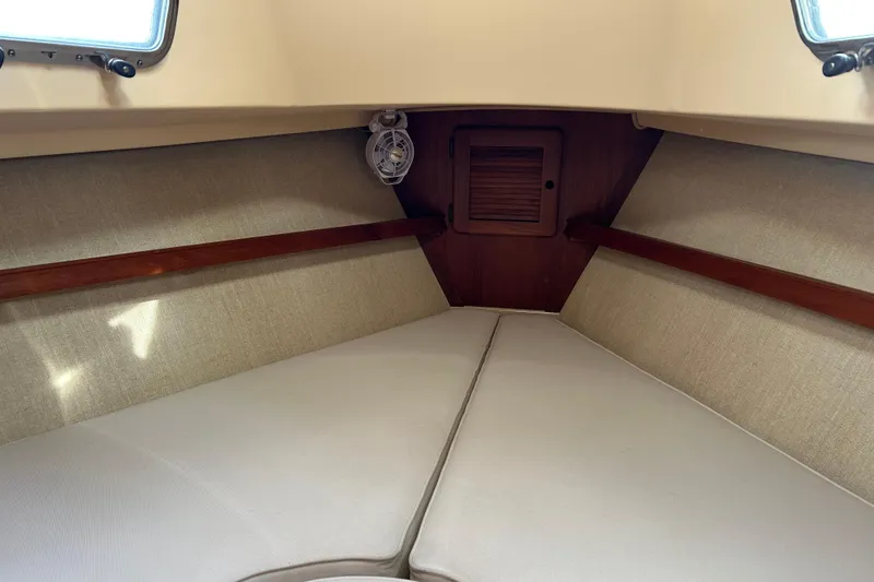 Slide: The Image of Interior cabin of a 1997 Island Packet 29 sailboat, featuring cozy beige cushions. - 5