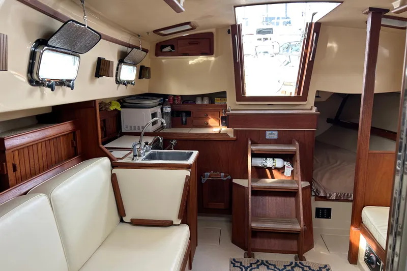 Slide: The Image of Interior of 1997 Island Packet 29 sailboat with cozy seating and compact kitchen area. - 7