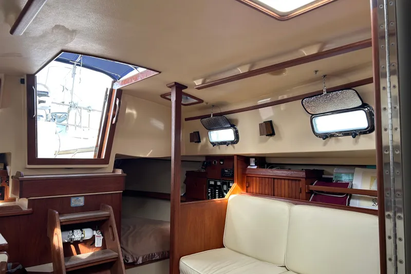 Slide: The Image of Interior of 1997 Island Packet 29 sailboat, featuring cozy seating and wooden accents. - 8