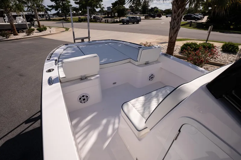 Slide: The Image of 2026 Twin Vee 22 Baycat boat interior with white seating and speakers, parked outdoors. - 21