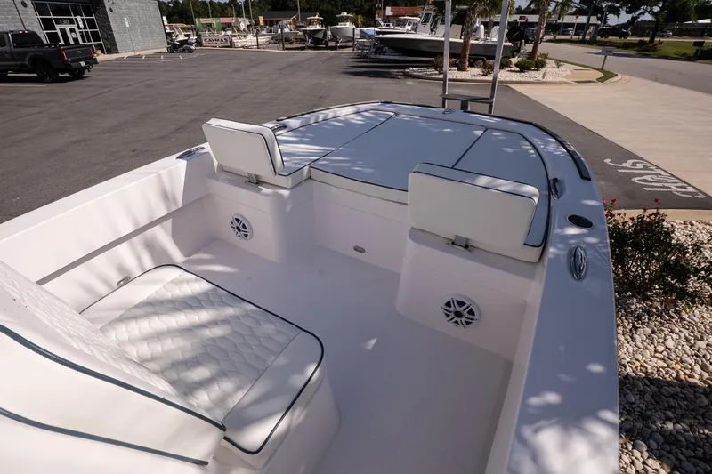 Slide: The Image of 2026 Twin Vee 22 Baycat boat interior with cushioned seating and speakers, parked outdoors. - 22