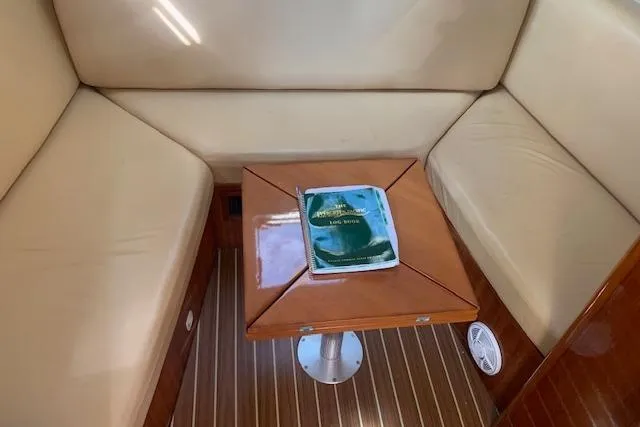 Slide: The Image of 2004 Mainship Pilot 30-II cabin interior with wooden table and beige seating. - 14